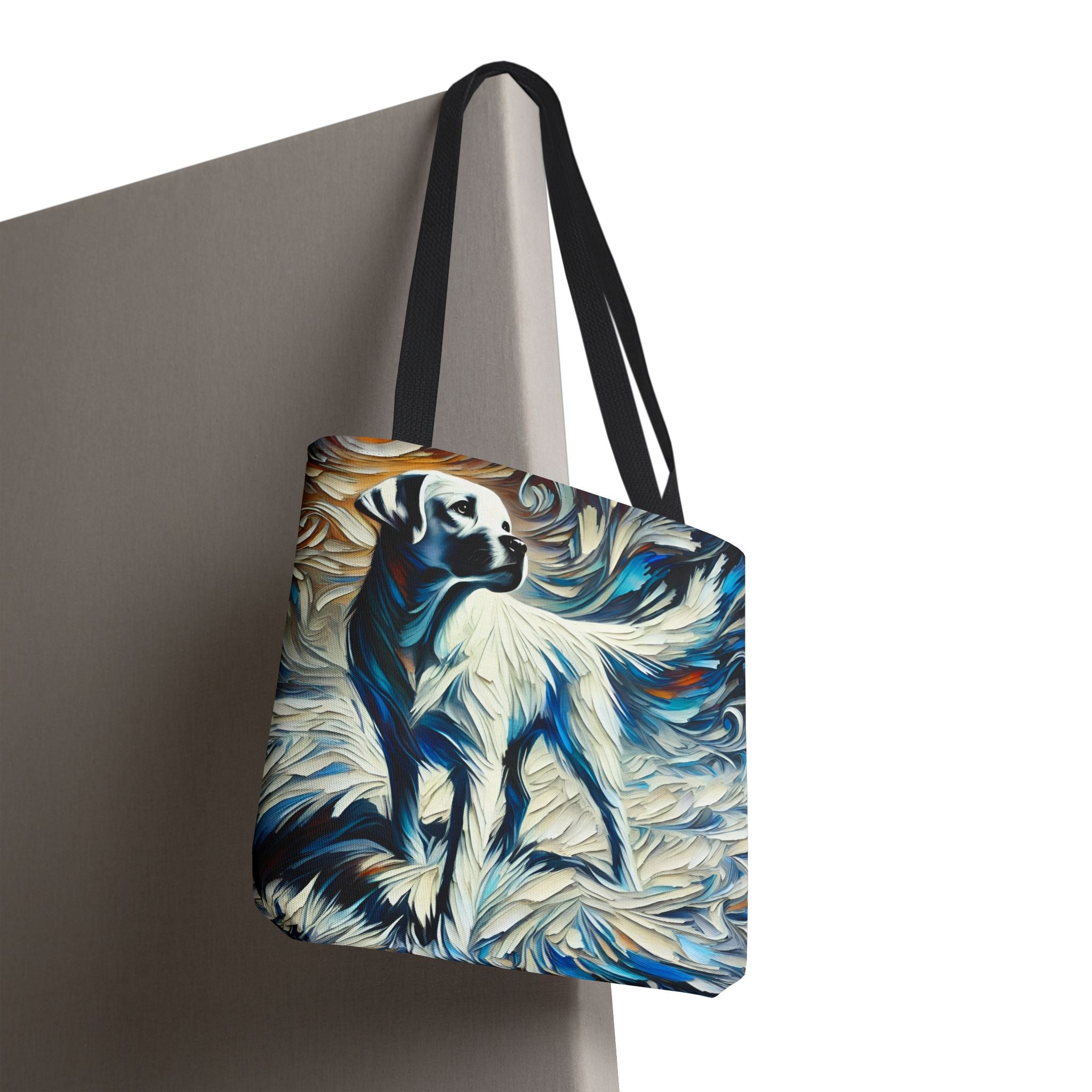 A tote bag with black handles, featuring a stylized painting of a white Labrador retriever surrounded by swirling blue, white, and brown brushstrokes, shown hanging against a neutral gray background.