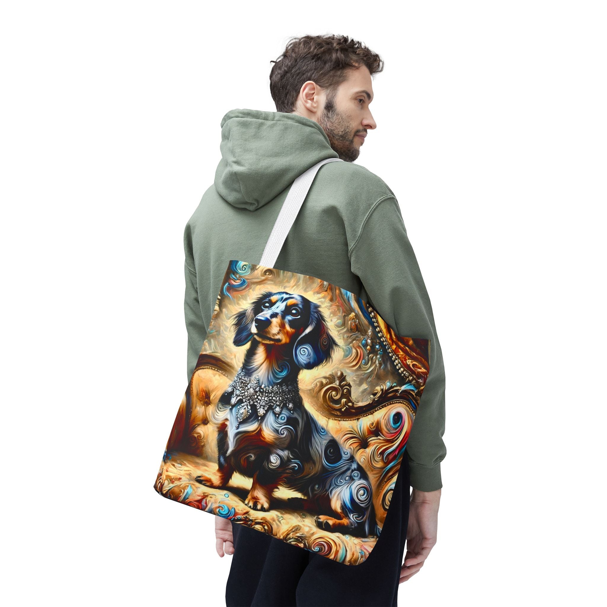A man wearing an olive green hoodie is shown from the back and side, carrying a canvas tote bag over his shoulder. The bag features a detailed, colorful graphic print of a dachshund surrounded by swirling abstract patterns in blue, orange, brown, and gold.