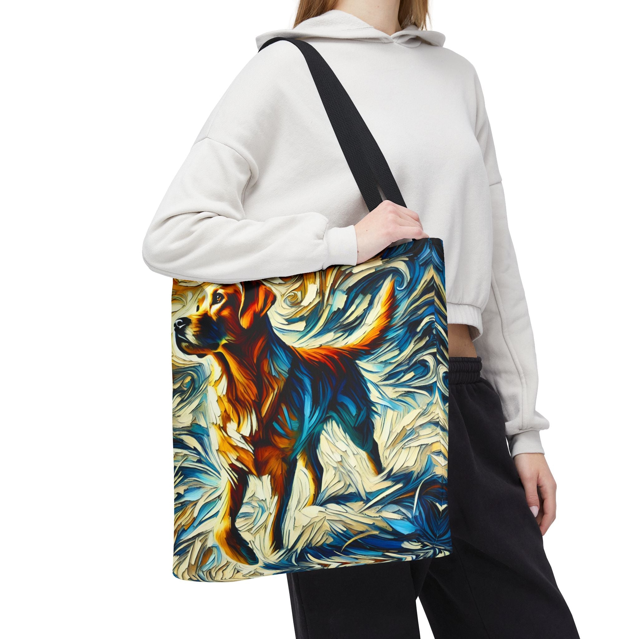 A person carries a canvas tote bag with a black shoulder strap. The bag features a colorful abstract painting of a yellow Labrador retriever in blue, orange, yellow, and white.