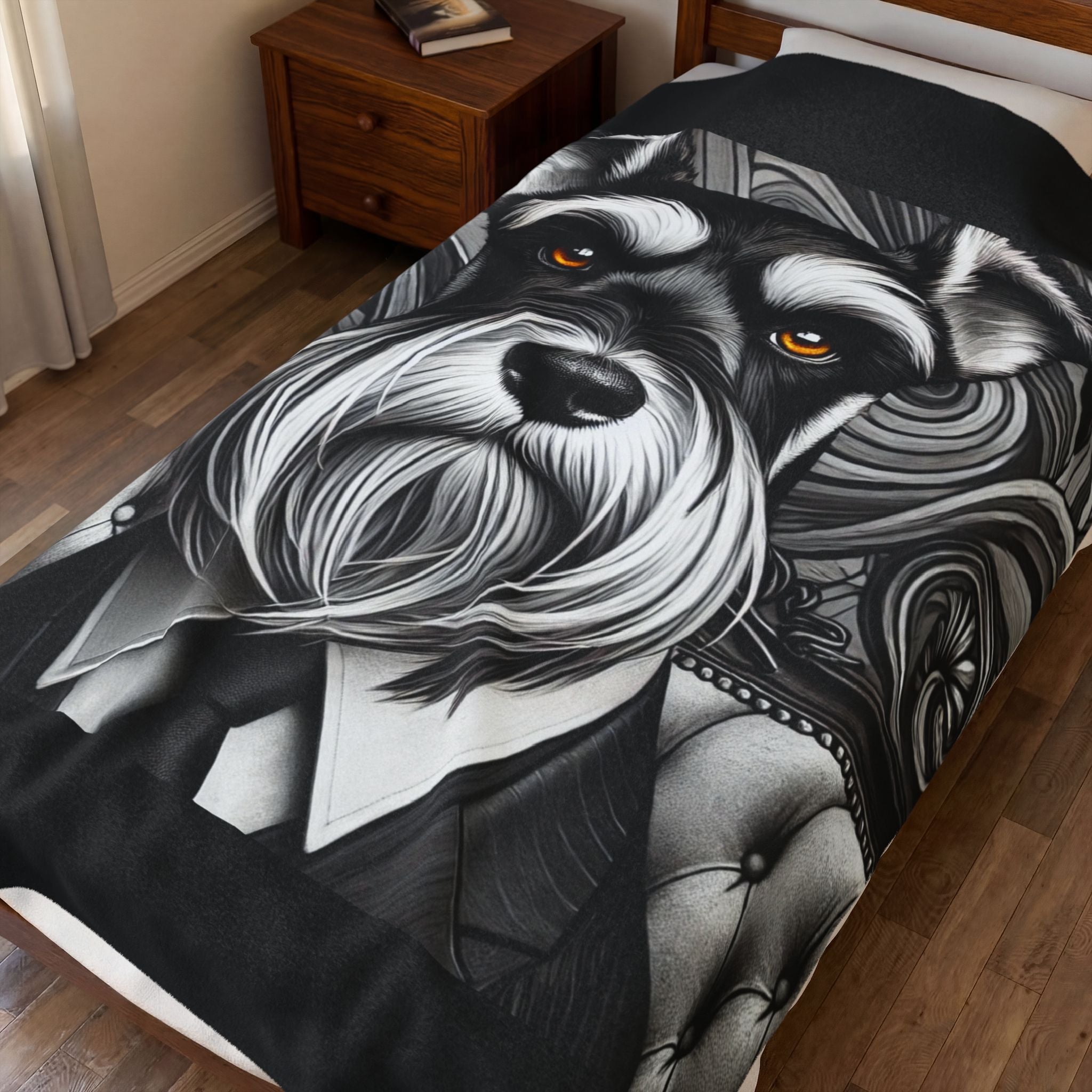 A black and white printed blanket featuring a stylized schnauzer portrait wearing a suit, shown on a bed in a bedroom with wood flooring and a wooden nightstand.