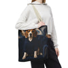 A person wearing a white cropped hoodie and black sweatpants carries a canvas tote bag over their shoulder. The tote bag features a printed graphic of a beagle dog sitting on a dark blue armchair against a swirling dark background.