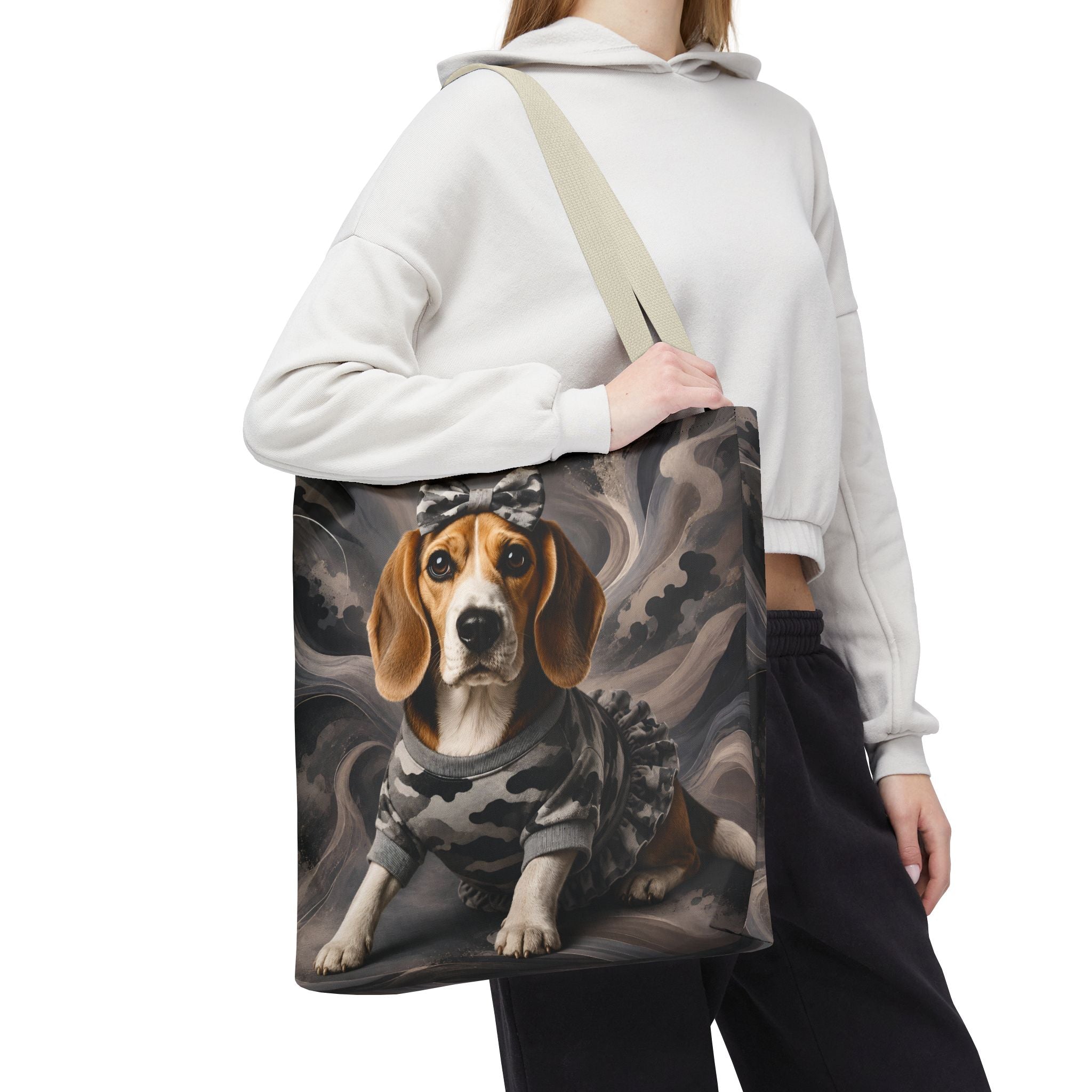 A person wearing a white cropped hoodie and black sweatpants carries a canvas tote bag. The bag features a printed illustration of a beagle dog wearing a gray camouflage sweater and a small bow against a smoky gray background.