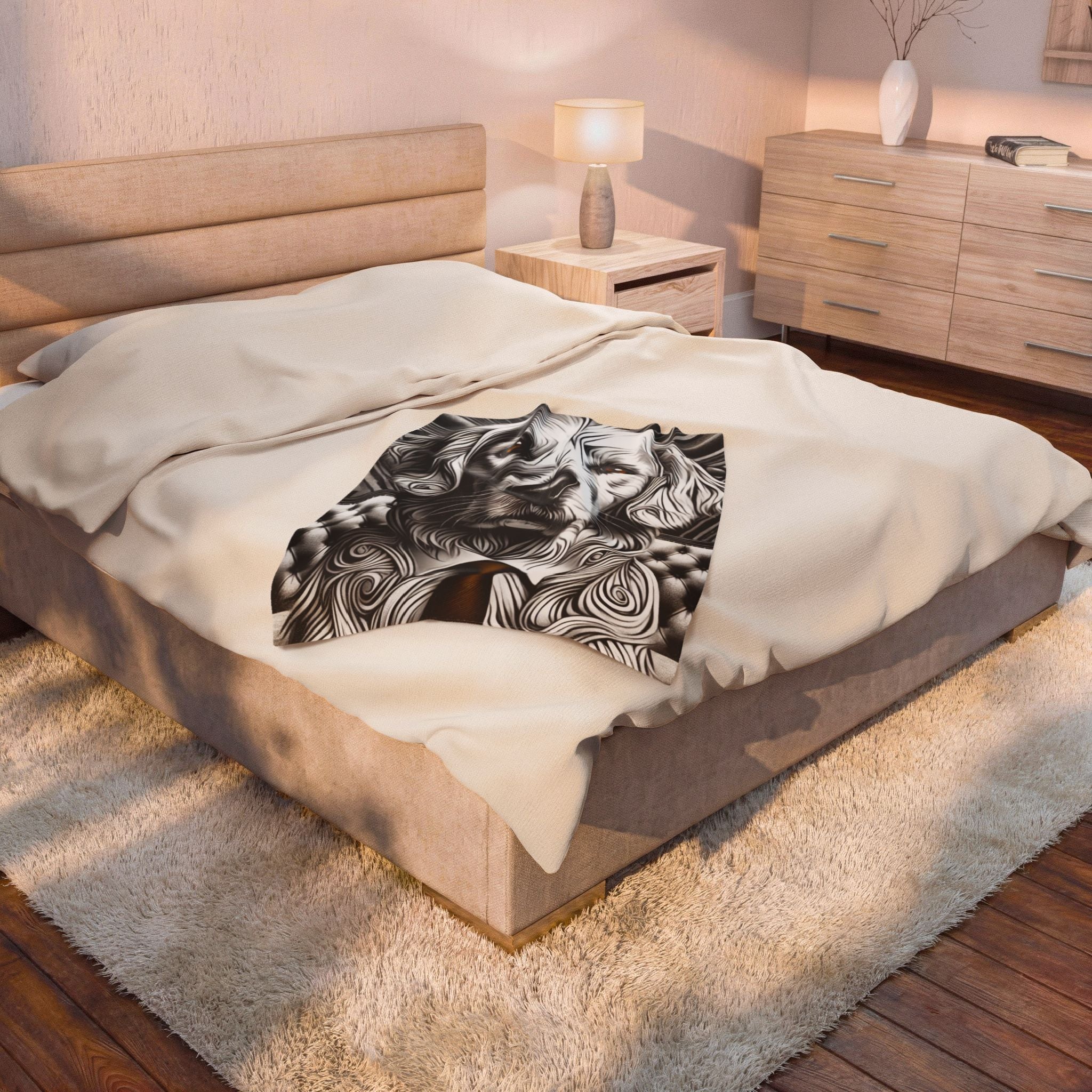 A bed in a modern bedroom setting, featuring a cream-colored upholstered frame, beige bedding, and a black and white abstract patterned throw blanket draped across the center.
