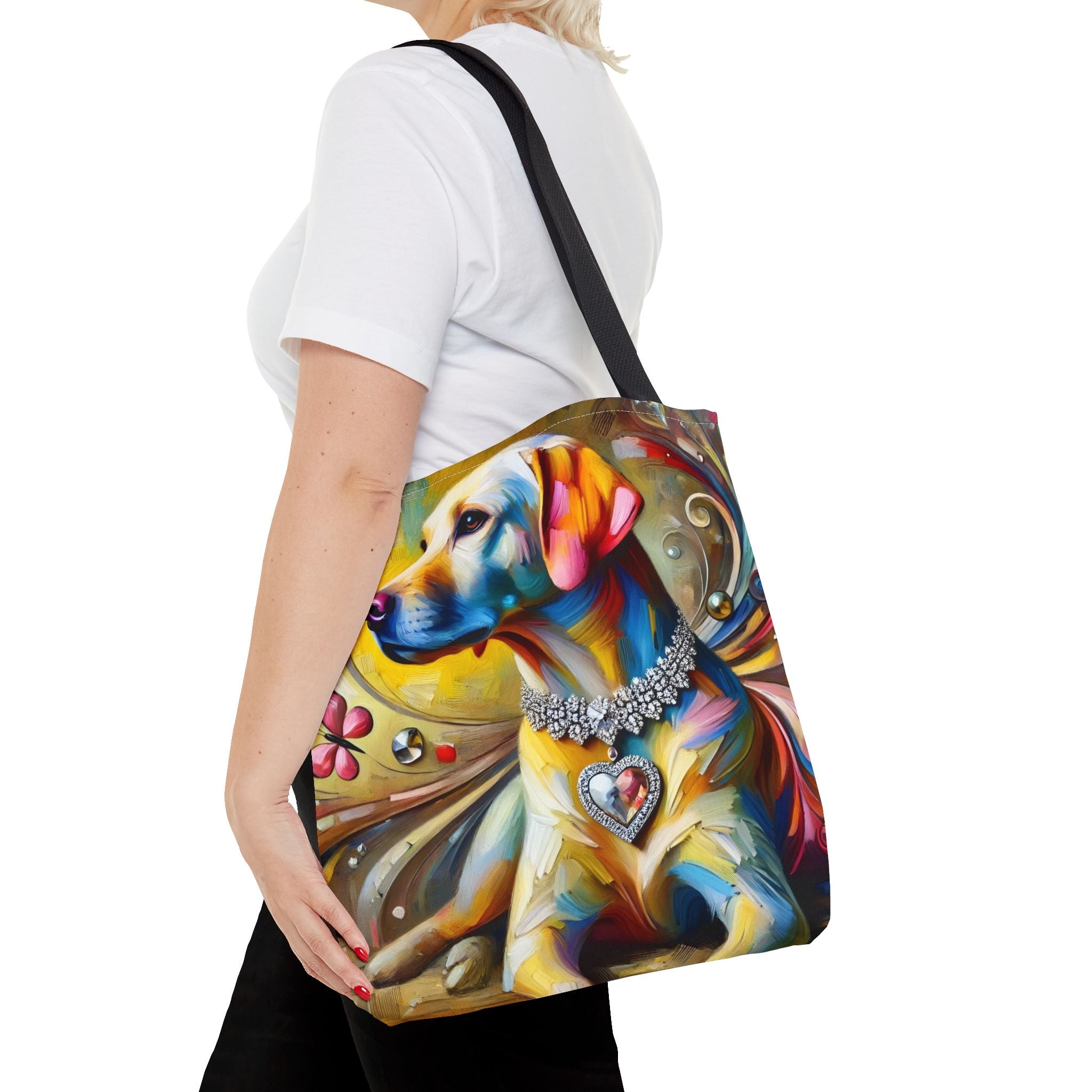 A woman carries a colorful tote bag featuring a stylized, multicolored painting of a yellow Labrador retriever wearing a jeweled collar, against a plain white background.