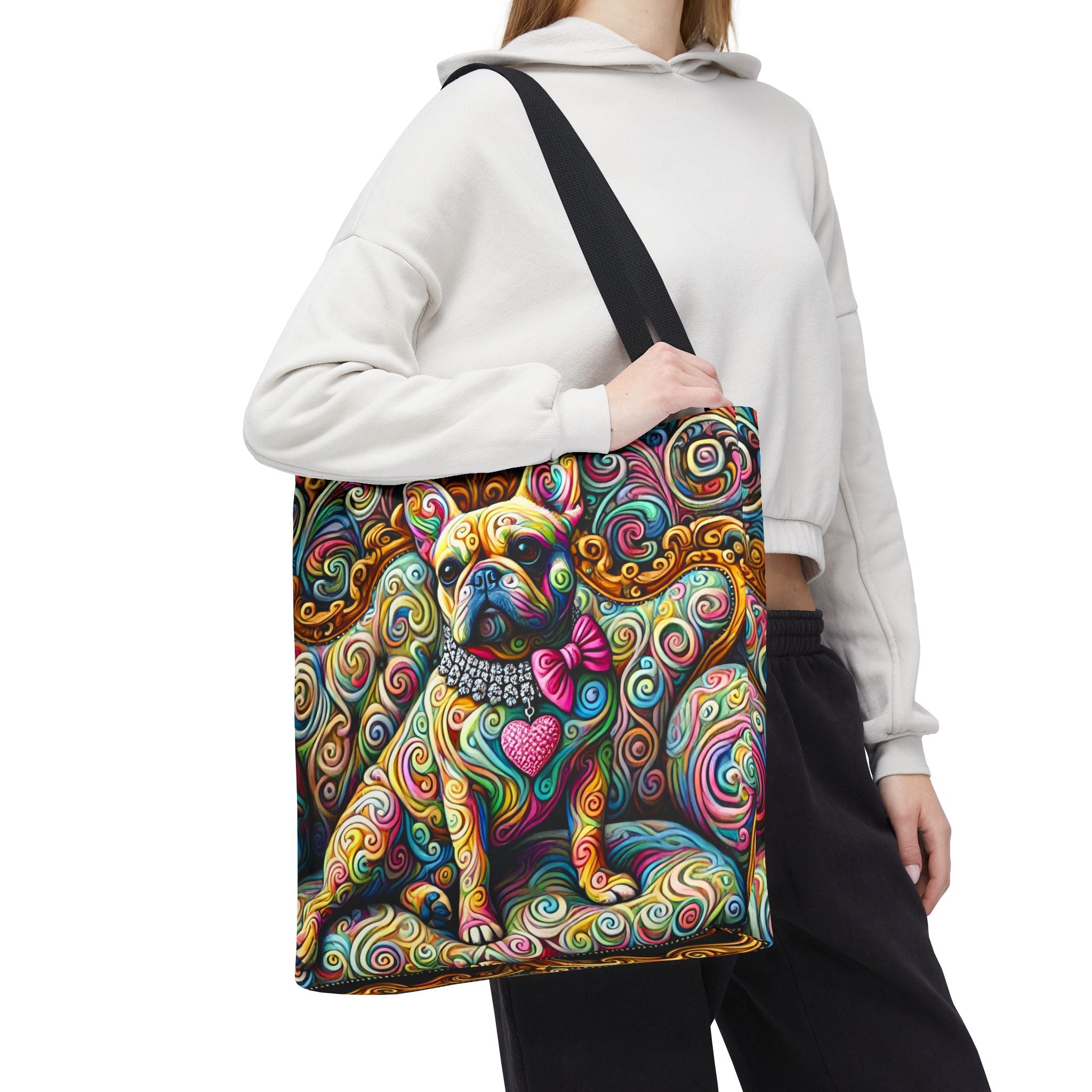 A person wearing a white cropped hoodie and black pants carries a large shoulder tote bag featuring a colorful, psychedelic illustration of a French Bulldog with swirl patterns and a pink bow tie, against a plain white background.