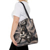 A woman wearing a white t-shirt and black pants carries a canvas tote bag over her shoulder. The bag features a detailed graphic print of a black French Bulldog wearing a camouflage shirt and a bow, set against a smoky gray background.