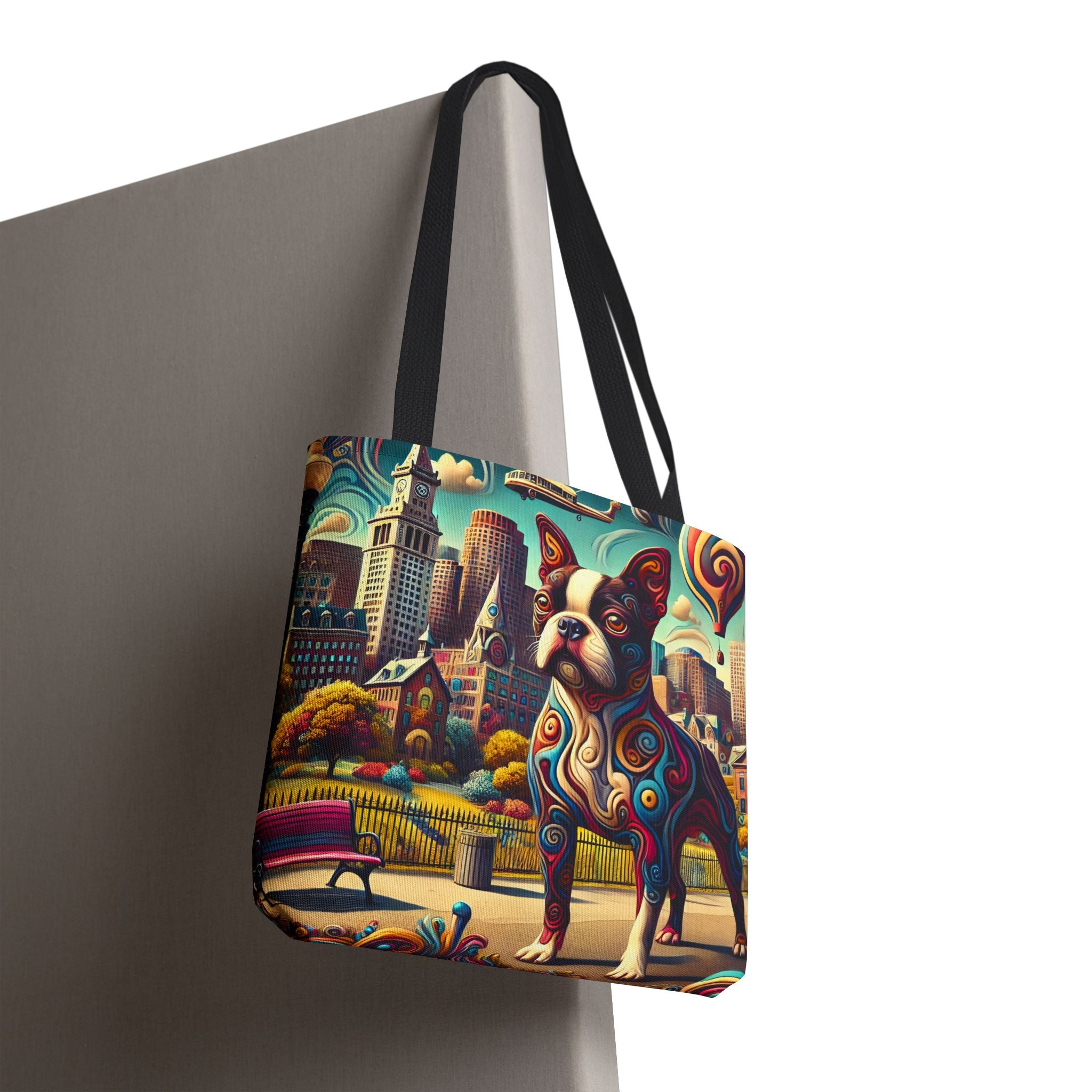 A tote bag with black handles, featuring a colorful, stylized illustration of a Boston Terrier dog in front of a city skyline. The bag is shown hanging against a gray display stand on a white background.
