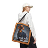 A woman wearing a white cap and white hoodie carries a canvas tote bag with a printed dachshund wearing denim overalls. The bag has a brown leather-look border and a black shoulder strap, shown against a plain white background.