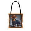 A tote bag with black shoulder straps and a tan border, featuring a printed graphic of a dachshund wearing blue denim overalls against a gray studio background.