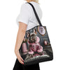 A woman wearing a white t-shirt and black pants carries a black tote bag with a printed graphic of a French bulldog in a pink jacket. The background is solid white.