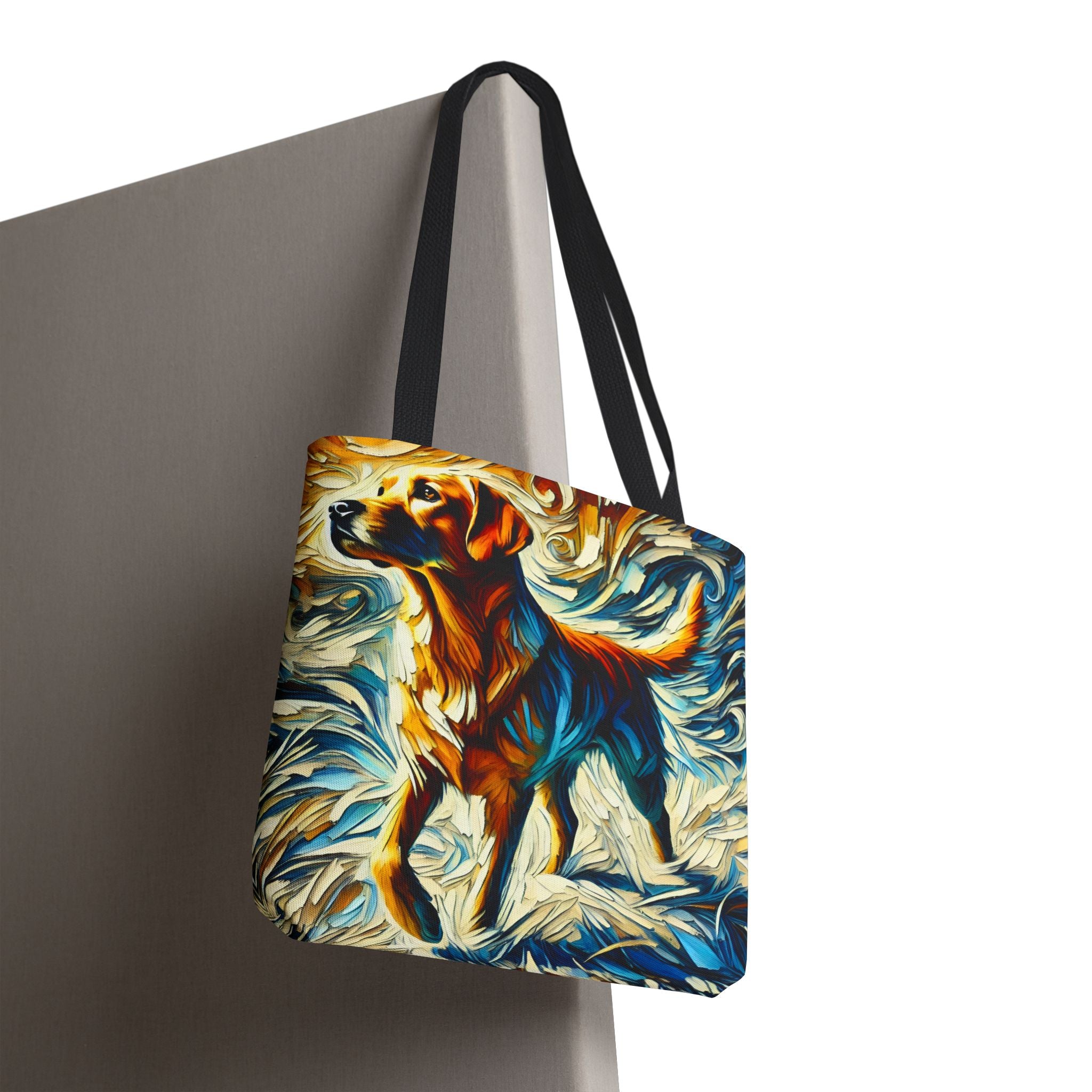 A tote bag with black shoulder straps, featuring a colorful abstract painting of a yellow Labrador retriever in warm orange, brown, and blue tones against a cream and blue background, shown hanging against a gray wall.