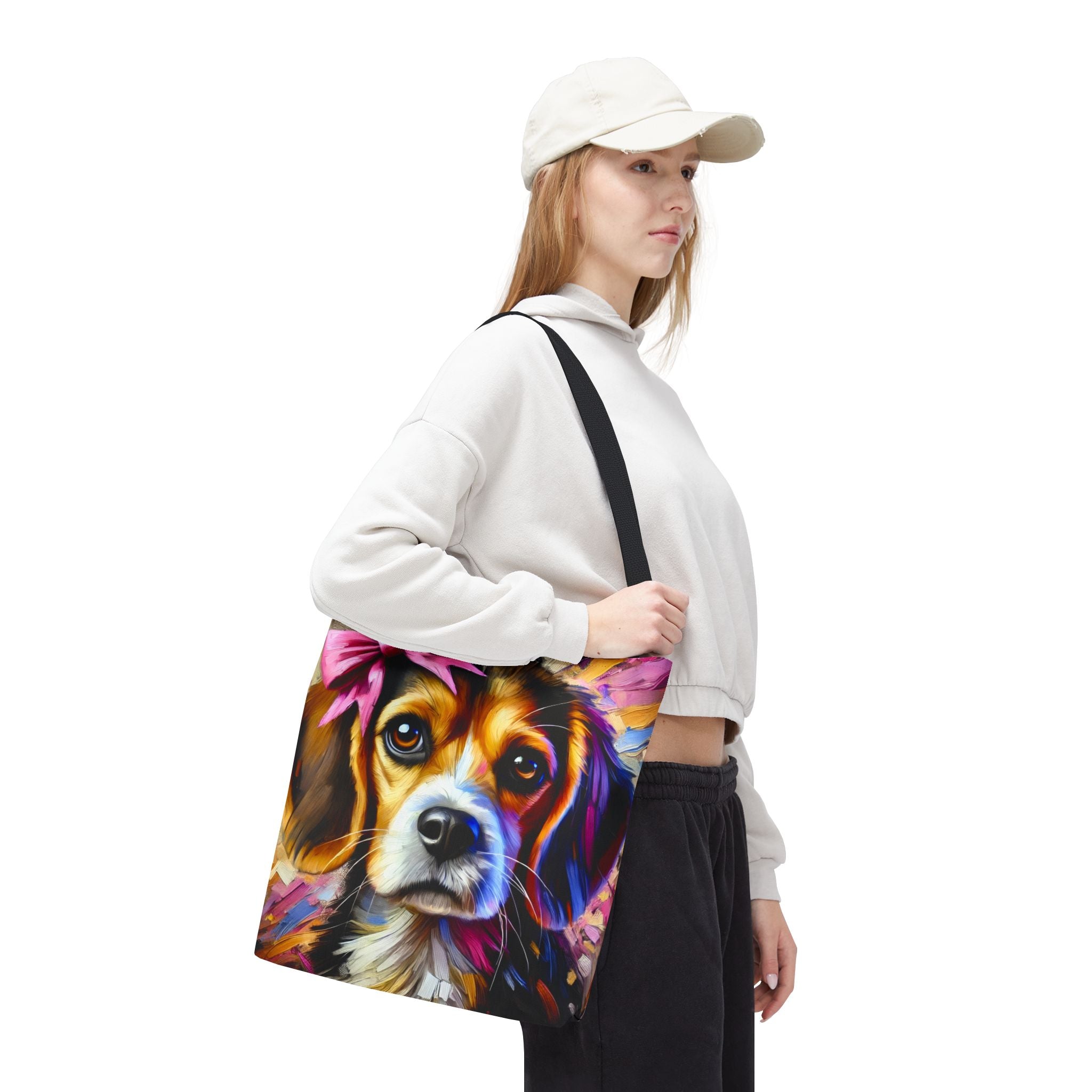 A woman wearing a white sweatshirt, black pants, and a white cap carries a canvas tote bag featuring a colorful, stylized portrait of a beagle on a plain white background.