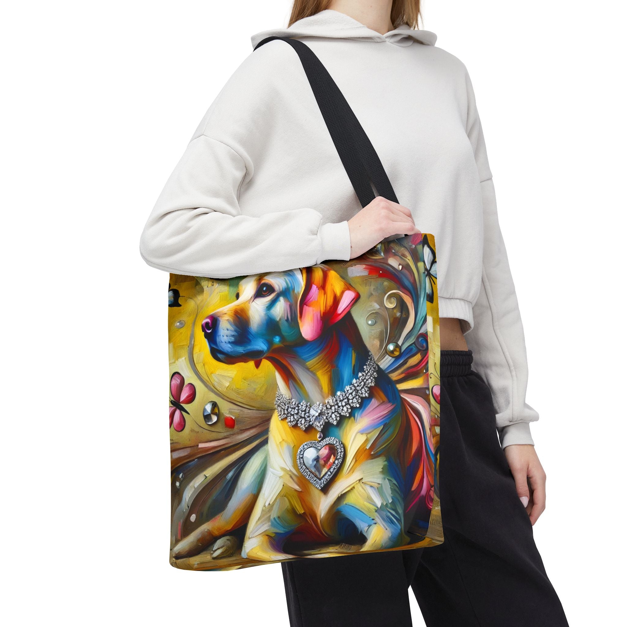 A person carries a large tote bag with a colorful artistic print of a yellow Labrador retriever wearing a jeweled collar. The background is solid white.