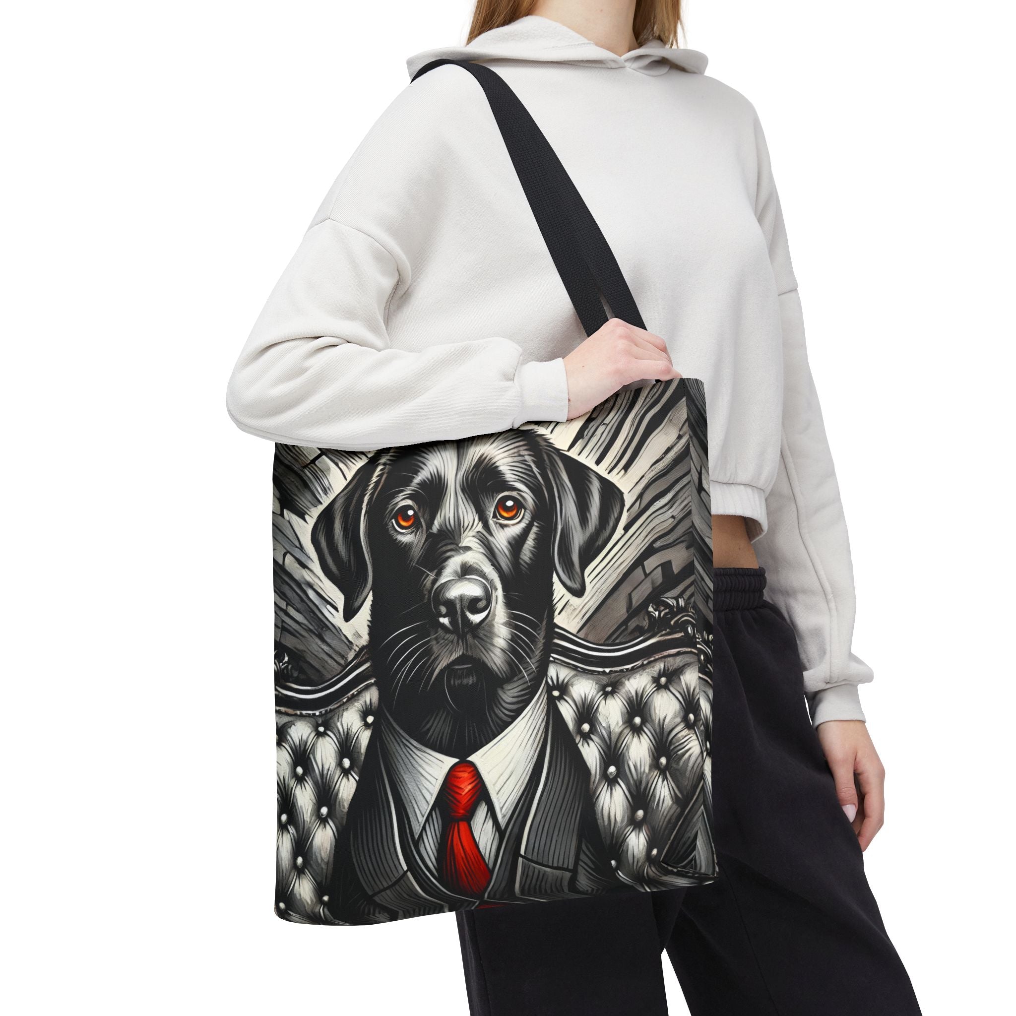 A person wearing a white cropped hoodie and black pants carries a black shoulder tote bag featuring a detailed graphic print of a black Labrador Retriever dressed in a suit with a red tie, set against a plain white background.