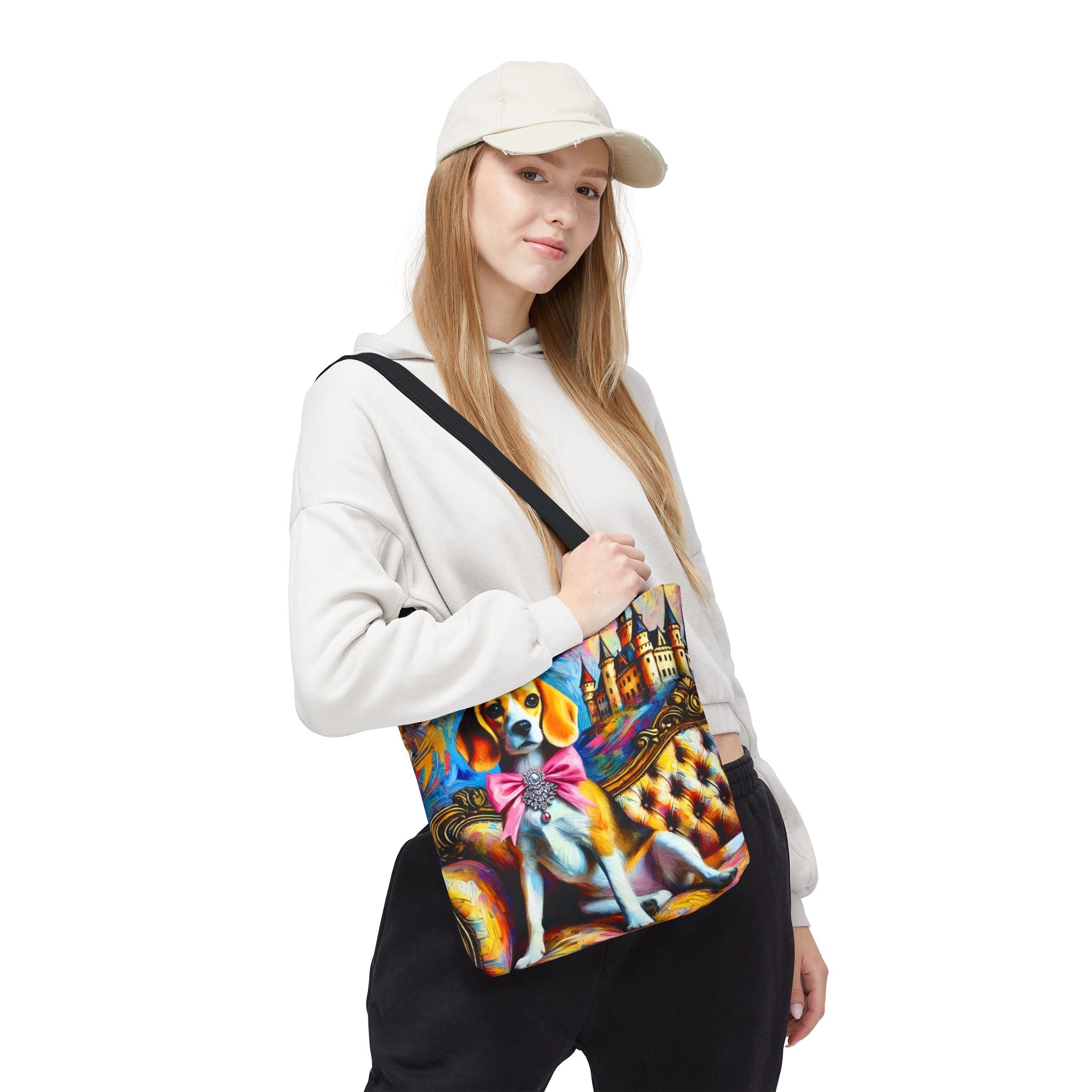 A woman wearing a beige cap, white hoodie, and black sweatpants carries a colorful crossbody bag featuring a painted beagle dog on a tufted sofa.