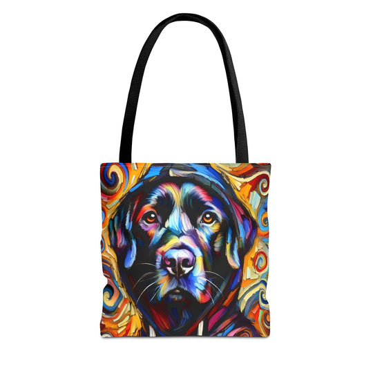 A tote bag with black handles featuring a colorful, stylized portrait of a black Labrador retriever surrounded by swirling abstract patterns in red, orange, yellow, blue, and white, shown on a plain white background.