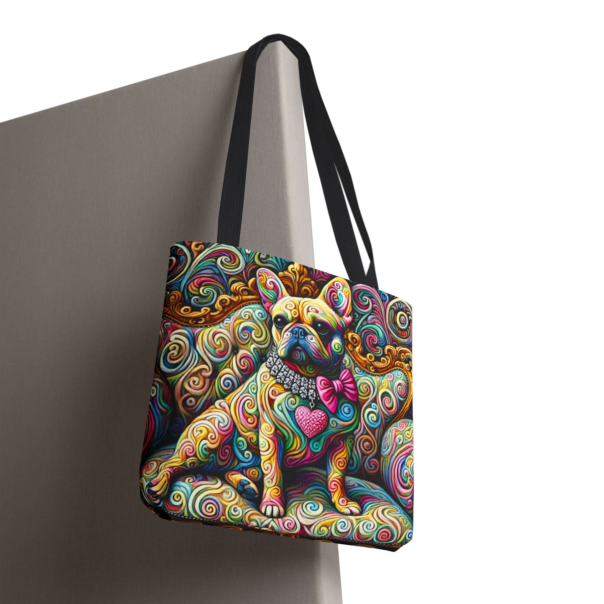 A tote bag with black shoulder straps, featuring a colorful, psychedelic cartoon French Bulldog illustration, shown hanging against a gray wall on a white background.