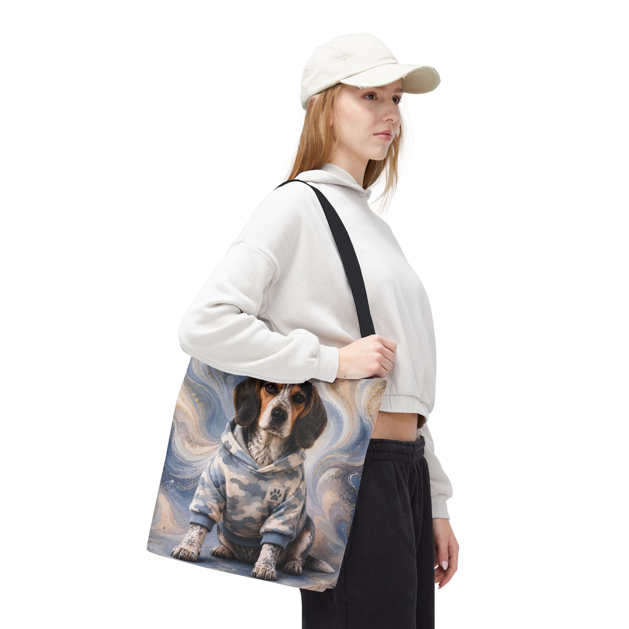 Woman carrying a Blue Tick Beagle Tote Bag with black handles, featuring a speckled beagle in a light blue camouflage hoodie on a blue, cream, and gold swirl background.
