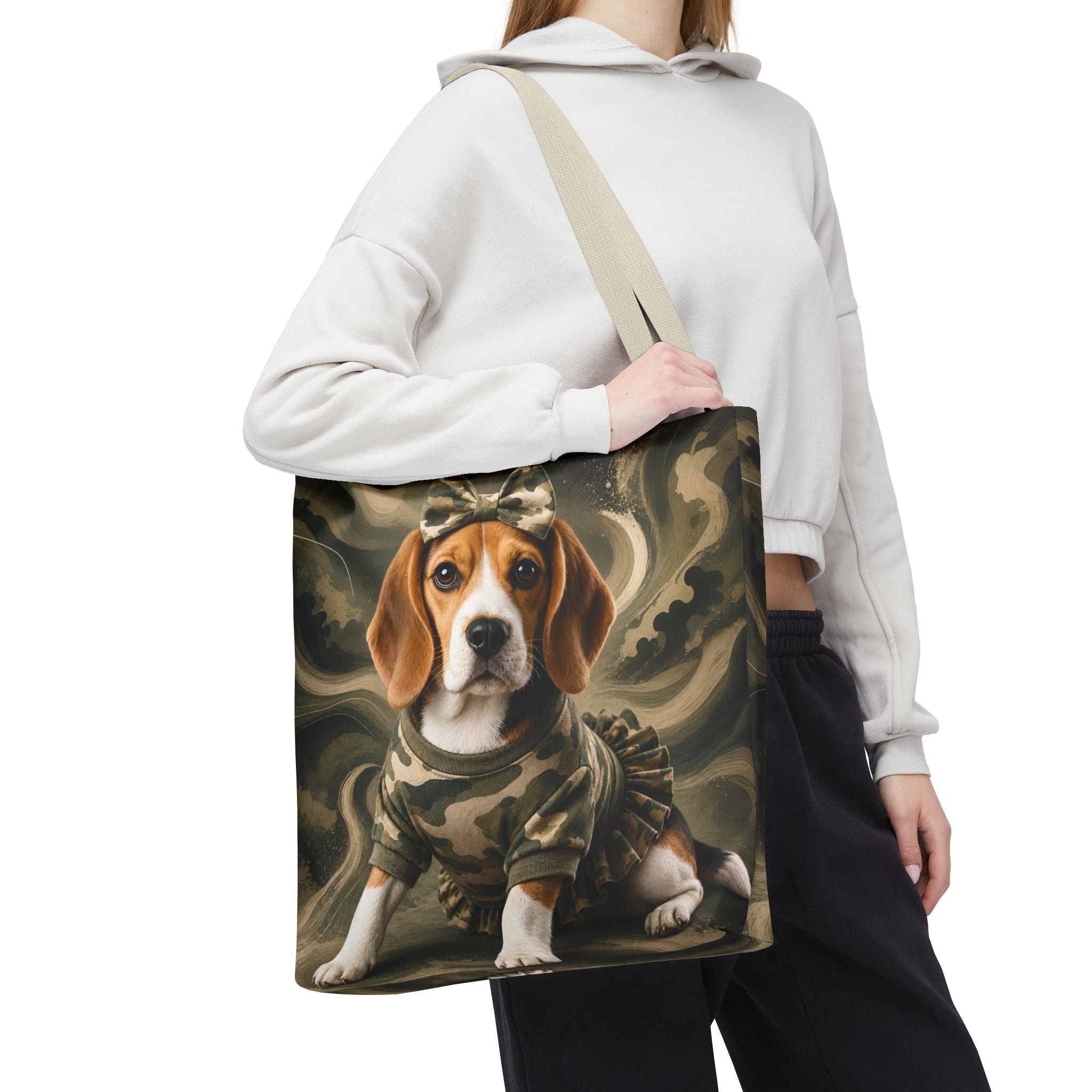 A person wearing a white cropped hoodie and black sweatpants carries a canvas tote bag over their shoulder. The bag features a printed graphic of a beagle dog wearing a military camouflage uniform against a smoky olive-green background.