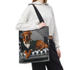 A person carries a large tote bag over their shoulder. The tote bag features a printed illustration of a fox red Labrador retriever dressed in a green suit and bow tie, lying on a tufted gray sofa.