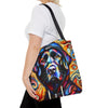 A woman wearing a white t-shirt and black pants carries a canvas tote bag with a colorful, stylized portrait of a black Labrador retriever on a plain white background.