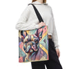 A person wearing a white cropped hoodie and black pants carries a large tote bag featuring a colorful geometric illustration of a French bulldog. The bag has a black shoulder strap and is shown against a plain white background.
